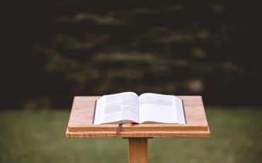 A podium tribune with the bible on it in a park and the bright sunlight in the background